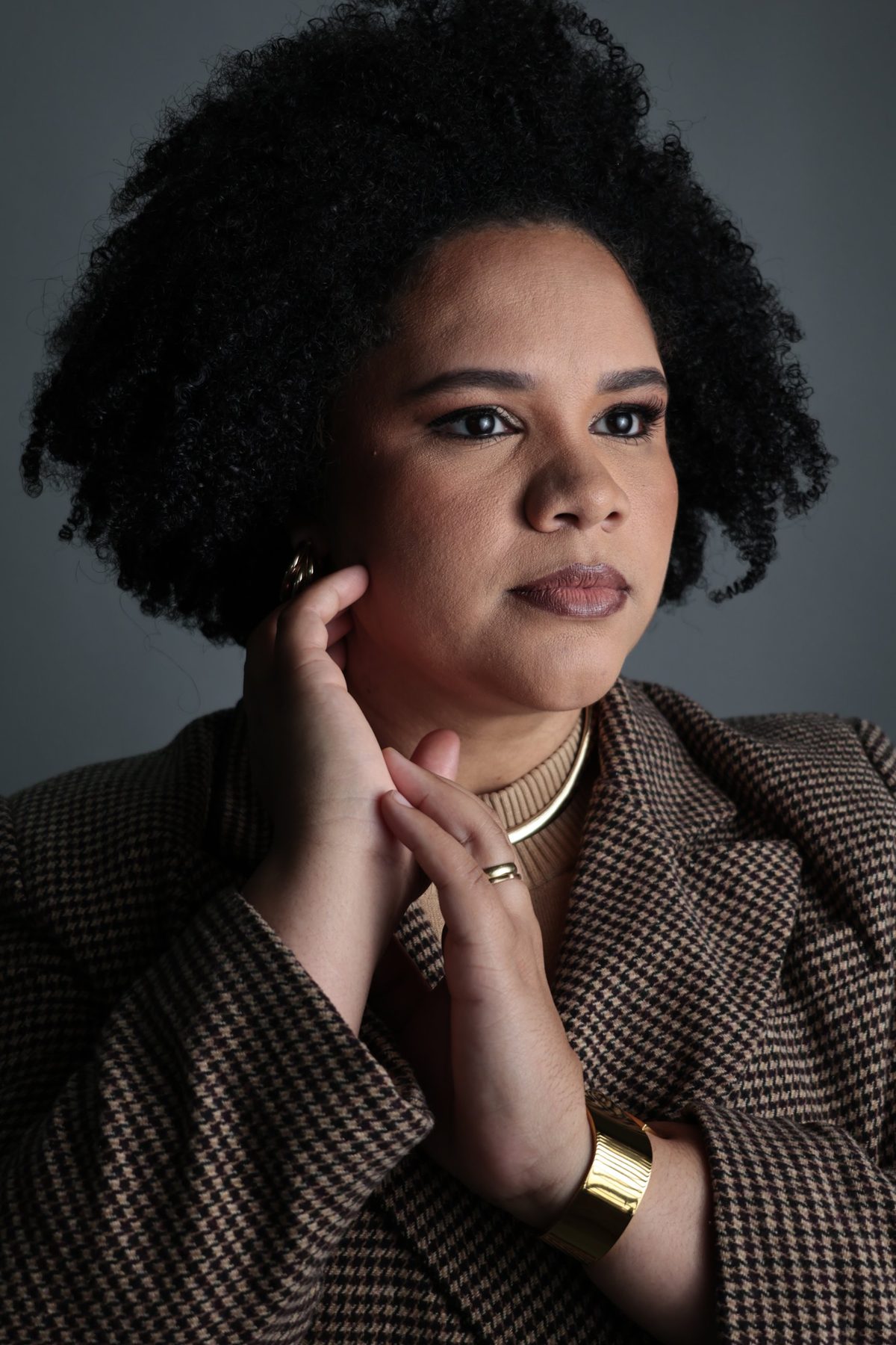 Retrato de perfil de mulher de blazer xadrez com bracelete dourado