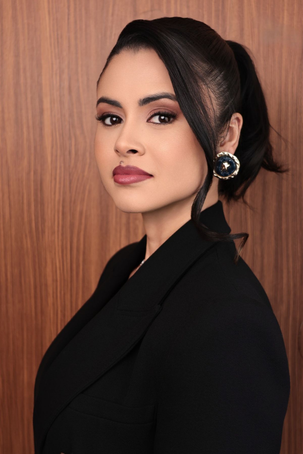 Retrato de perfil de mulher de blazer preto diante de madeira